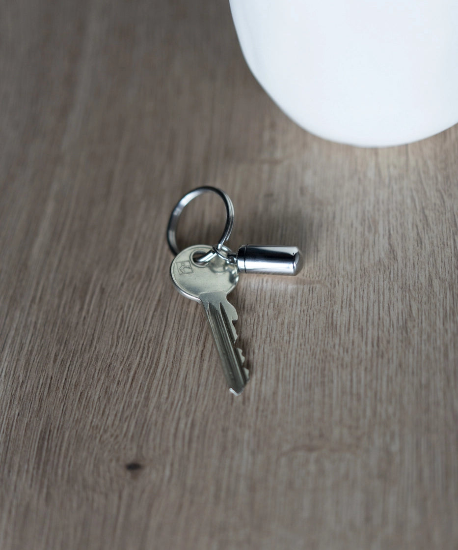 Schlüssel mit kleinem Anhänger Aschekapsel auf Holztisch
